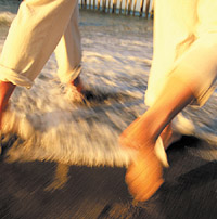 A Beach in Brunswick County, NC: An active couple runs through the water as small waves rush in